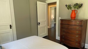 Une chambre à coucher avec un lit, une commode et un vase rempli de fleurs.
