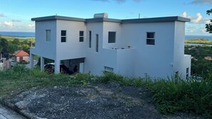 A modern two-story building with a flat roof, multiple windows, and a view of the ocean. - The Luxury Escape - Peaceful & Charming 3-bedroom villa w/ sea view (Vieux Fort)