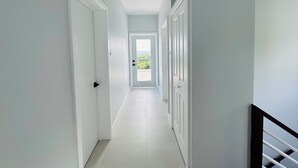 A hallway with white walls and doors, leading to a bright room with a view. - The Luxury Escape - Peaceful & Charming 3-bedroom villa w/ sea view (Vieux Fort)