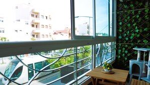 Una habitación con un ventanal grande, una mesa de madera con un florero y un rascador para gatos.