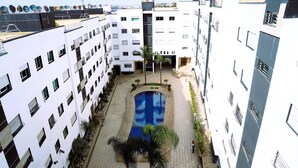 Un patio con piscina, rodeado por edificios de varios pisos con balcones y antenas parabólicas.