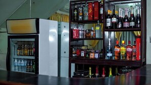 A bar area with a refrigerator stocked with beverages and a shelf with various liquor bottles. - Continental Suites Ltd (Abeokuta)