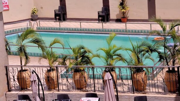 A pool area with chairs and potted plants. - Continental Suites Ltd (Abeokuta)