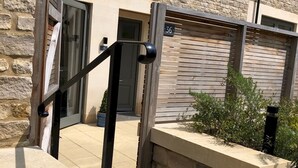 A stone building with a wooden door, a small potted plant, and a concrete bench. - Boutique private apartment convenient for city - Pass the Keys (Bath)