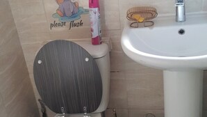 Un baño con inodoro, lavabo y un cubo de basura.
