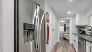 A modern kitchen with stainless steel appliances, white cabinetry, and a wooden floor. - Home Base for Winter Ski Adventure & Salt Lake City Events (Sandy)