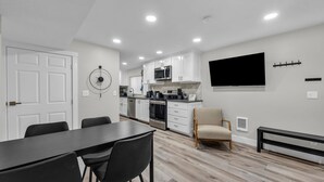 A modern kitchen with white cabinets, a microwave, and a large flat-screen TV. - Home Base for Winter Ski Adventure & Salt Lake City Events (Sandy)