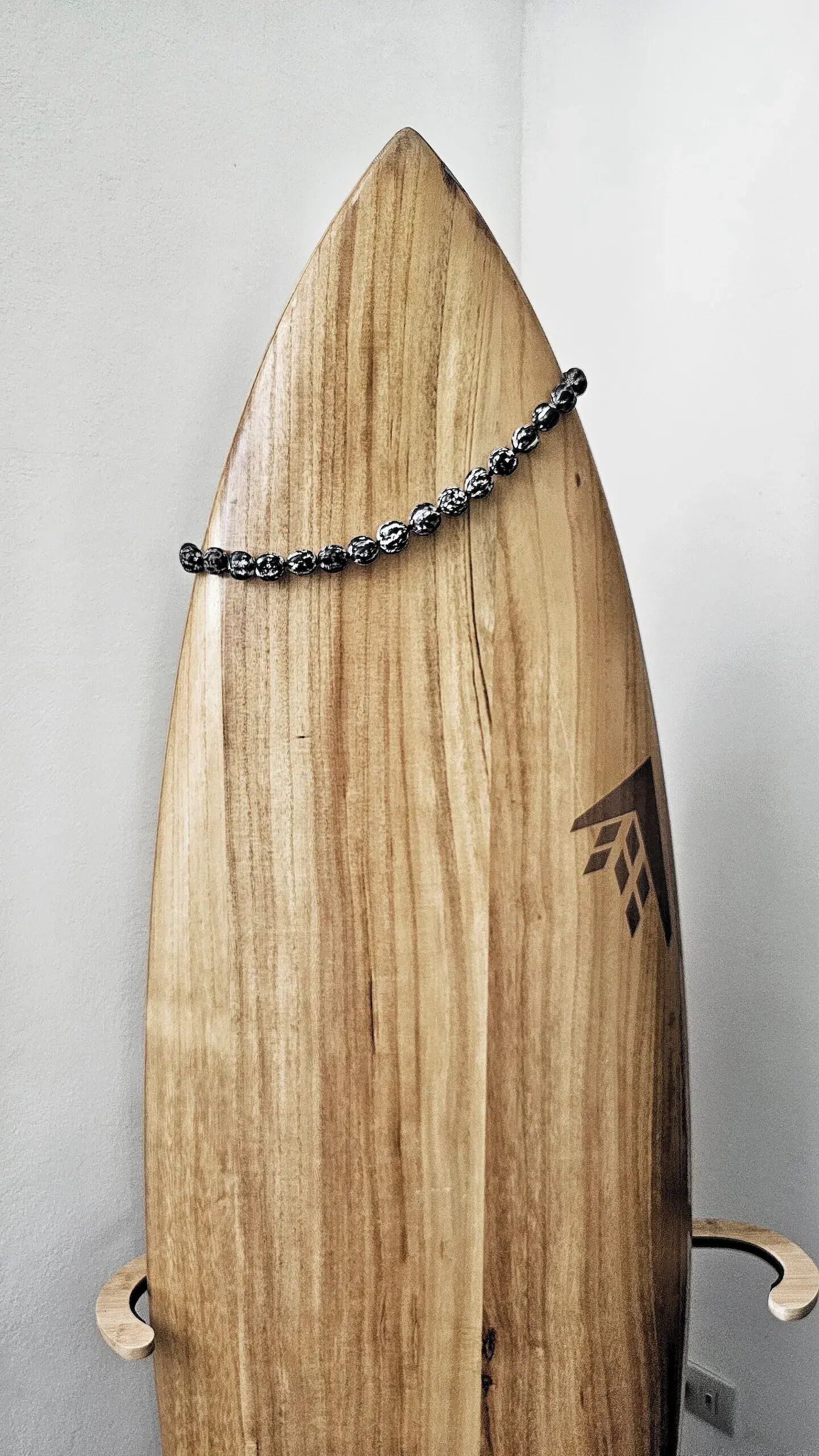 Ein Surfbrett aus Holz mit einer schwarzen Schmuckkette darauf.