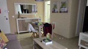 A modern living room with a sofa, coffee table, and a dining area with chairs and a table. - Hotel Onyx (Belgrade)
