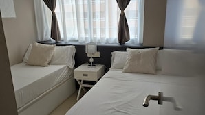 A hotel room with two beds, a nightstand, and a window with curtains. - Hotel Onyx (Belgrade)