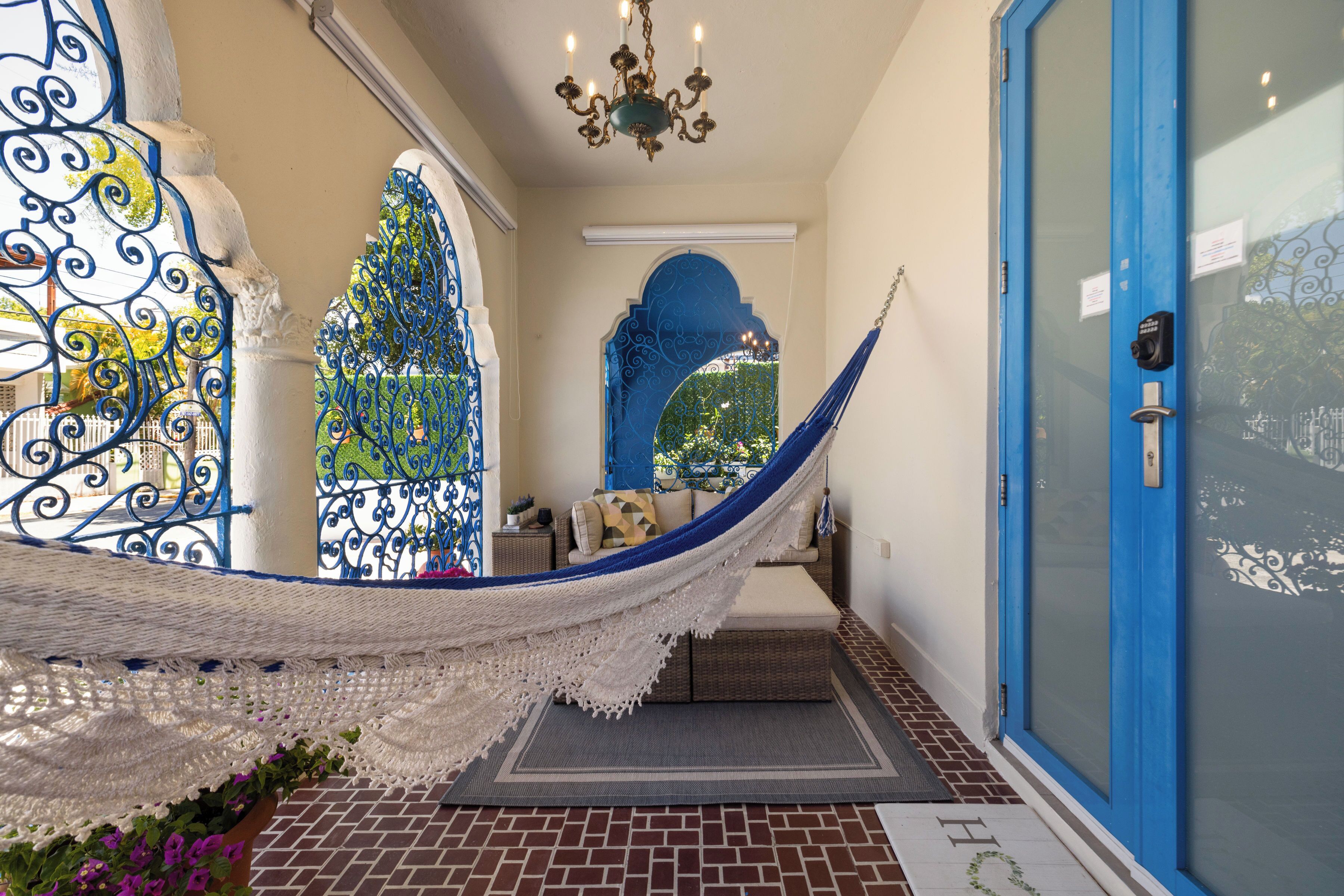 A hammock in a hallway with a blue door and decorative ironwork.