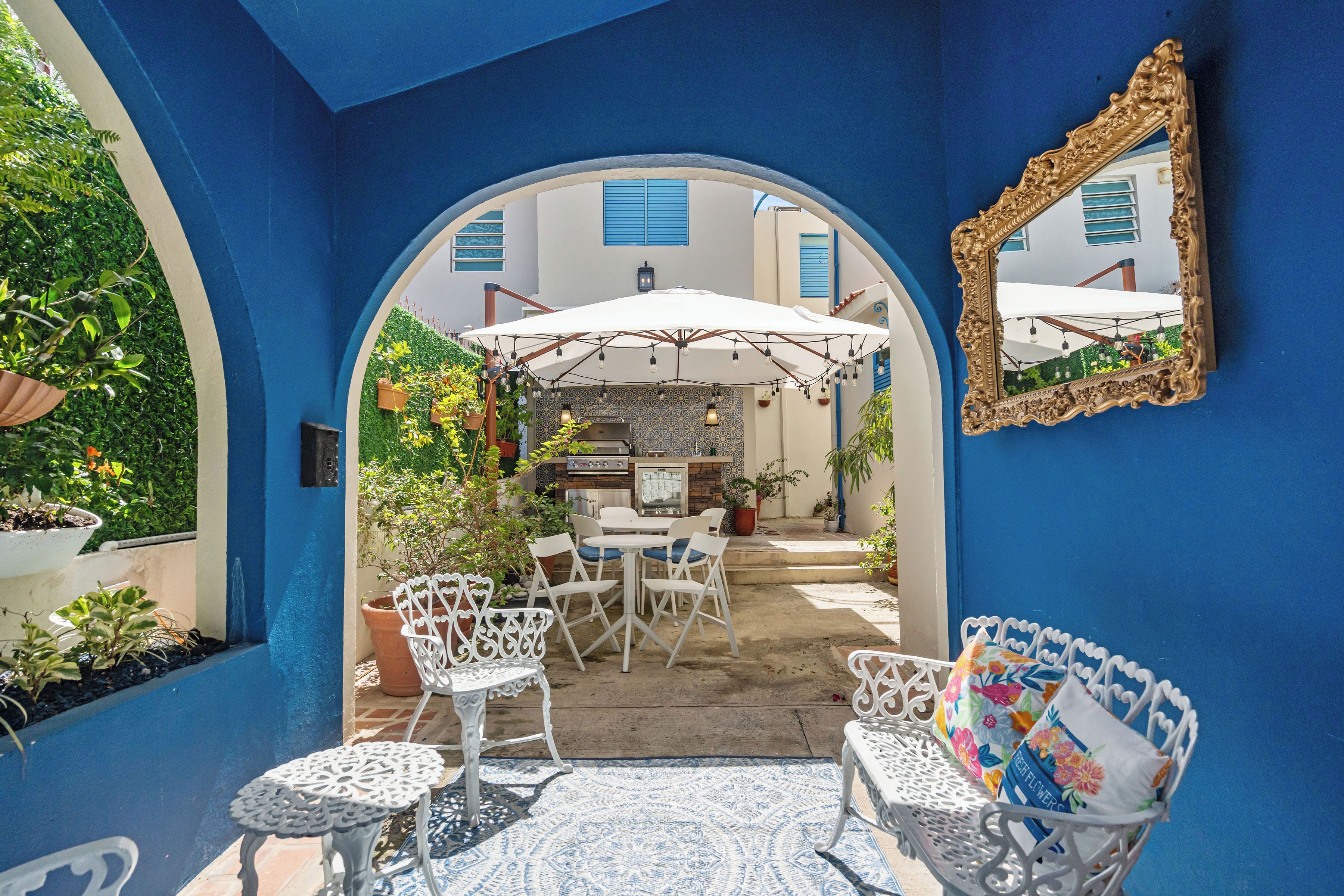 Une terrasse extérieure avec des meubles en métal blancs, un parasol blanc et des plantes en pot.