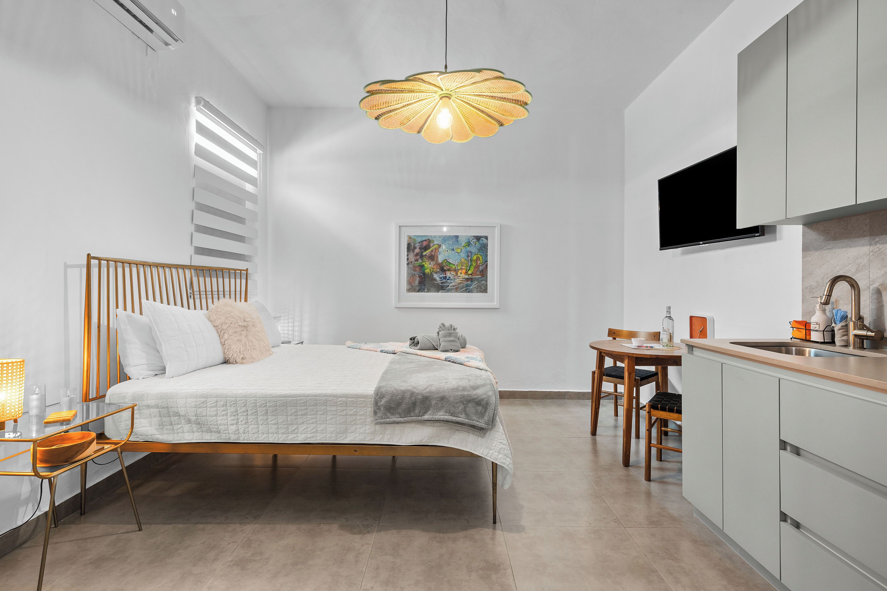A modern bedroom with a bed, bedside table, lamp, and a dining area with a table and chairs.