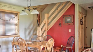 A dining area with a wooden table and chairs, a staircase, and a red wall. - Picturesque Cabin set on 150-acre farm, 5-minute drive to Chautauqua Institute (Mayville)