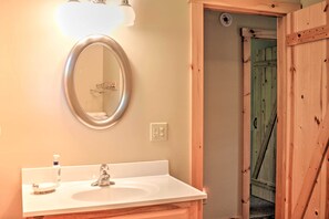 A bathroom with a white sink, a mirror, and a wooden door.