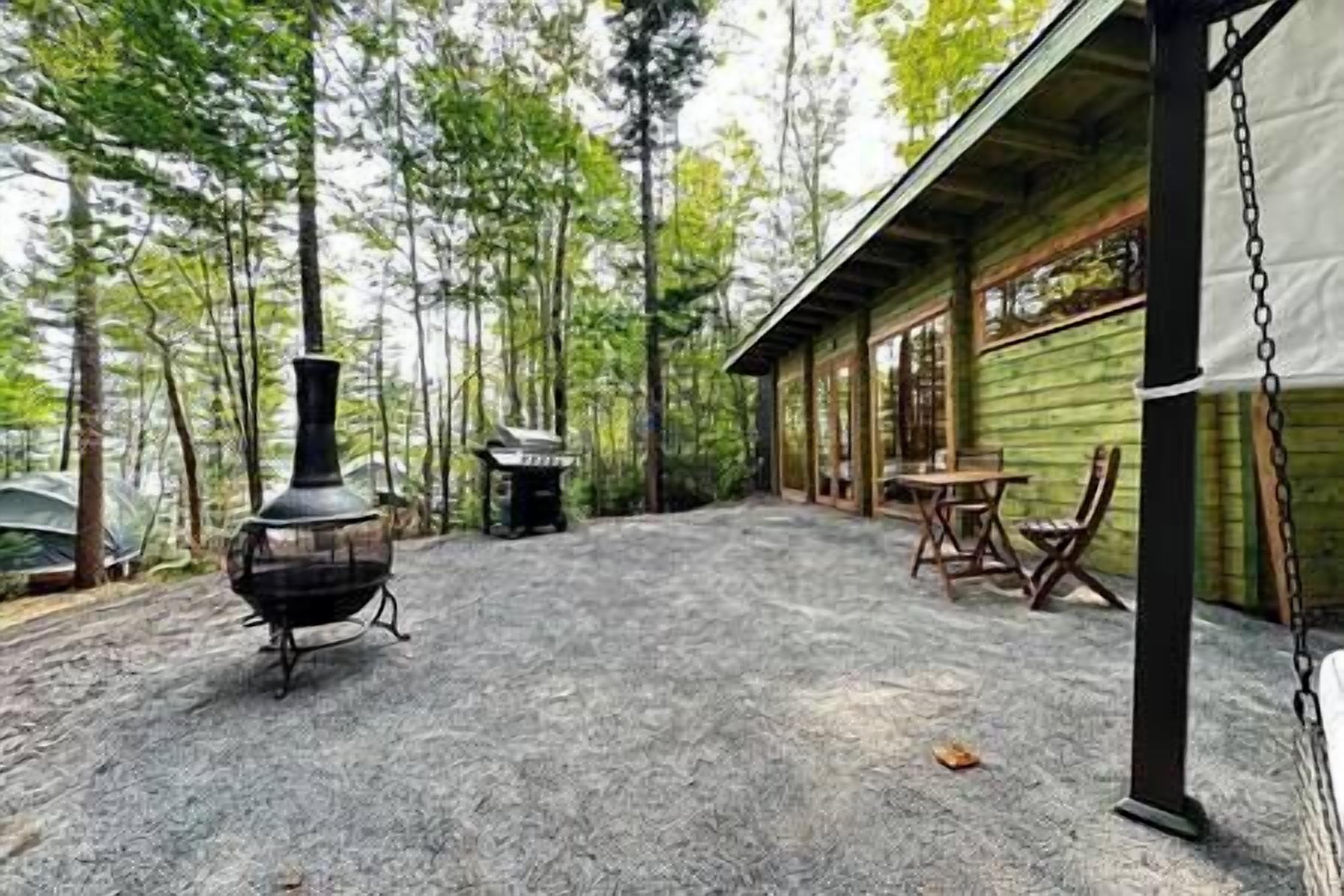 Eine rustikale Holzhütte mit einer Steinterrasse, einem Kaminofen und einem Essbereich mit Stühlen und einem Tisch.