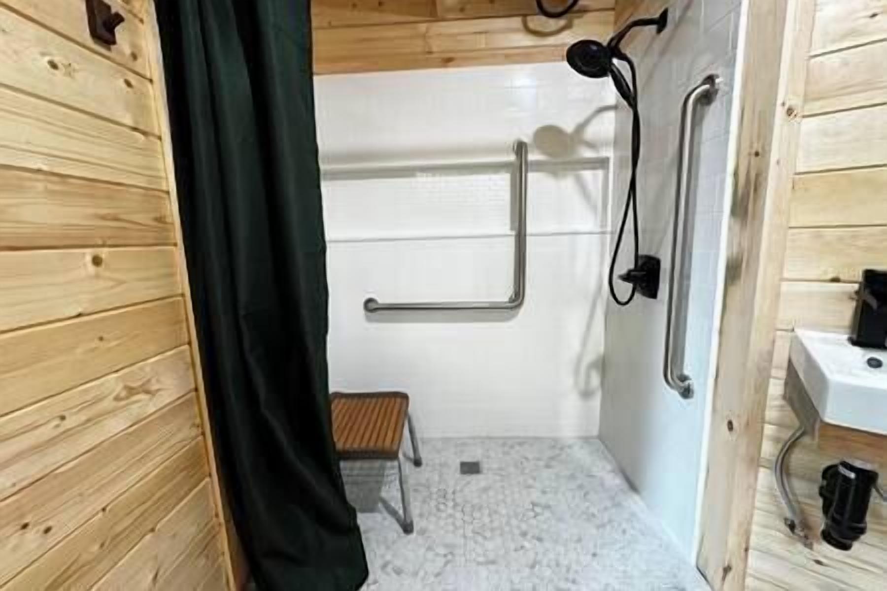 Un intérieur en bois avec un espace douche comprenant un banc et des barres d’appui.