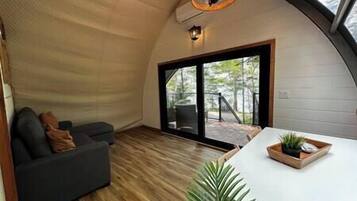 A cozy interior with a sofa, a dining table with a plant, and a large sliding glass door leading to an outdoor deck.