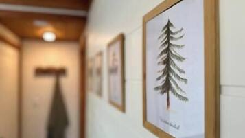 Un couloir orné de tableaux encadrés, dont une illustration remarquable représentant un arbre.