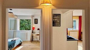 Een kamer met een bed, een bureau en een stoel, een raam met uitzicht op bomen en een poster aan de muur.