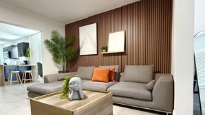 Una sala de estar moderna con un sofá, una mesa de centro y una obra de arte colgada en la pared.
