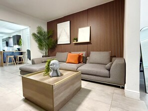 A modern living room with a sofa, a coffee table, and a wall-mounted artwork.