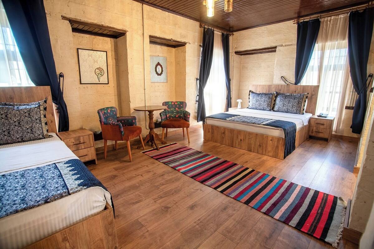A room with two beds, a small table, two chairs, and a rug.