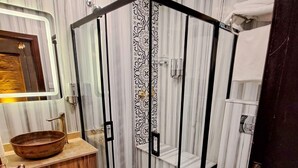 Un baño moderno con ducha de vidrio, tocador de madera y suelo de mármol.
