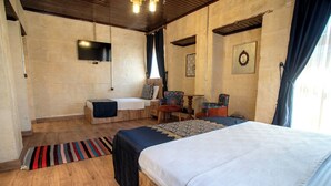 Un dormitorio con cama, escritorio, silla, televisor y ventana con cortinas.
