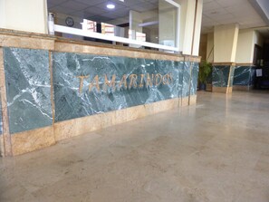 A reception desk with a marble counter and the name 'TAMARINDOS' engraved on it.