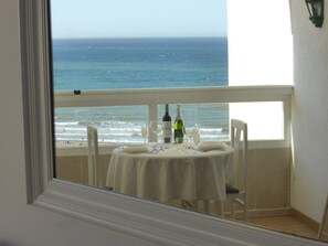 Un balcon avec une table dressée pour deux personnes, donnant sur l’océan.
