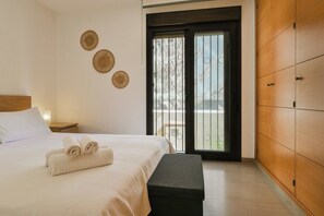 A hotel room with a bed, a bench, a sliding door to the balcony, and wall decor. - Lovely apartment 50m from the beach! (Fuengirola)
