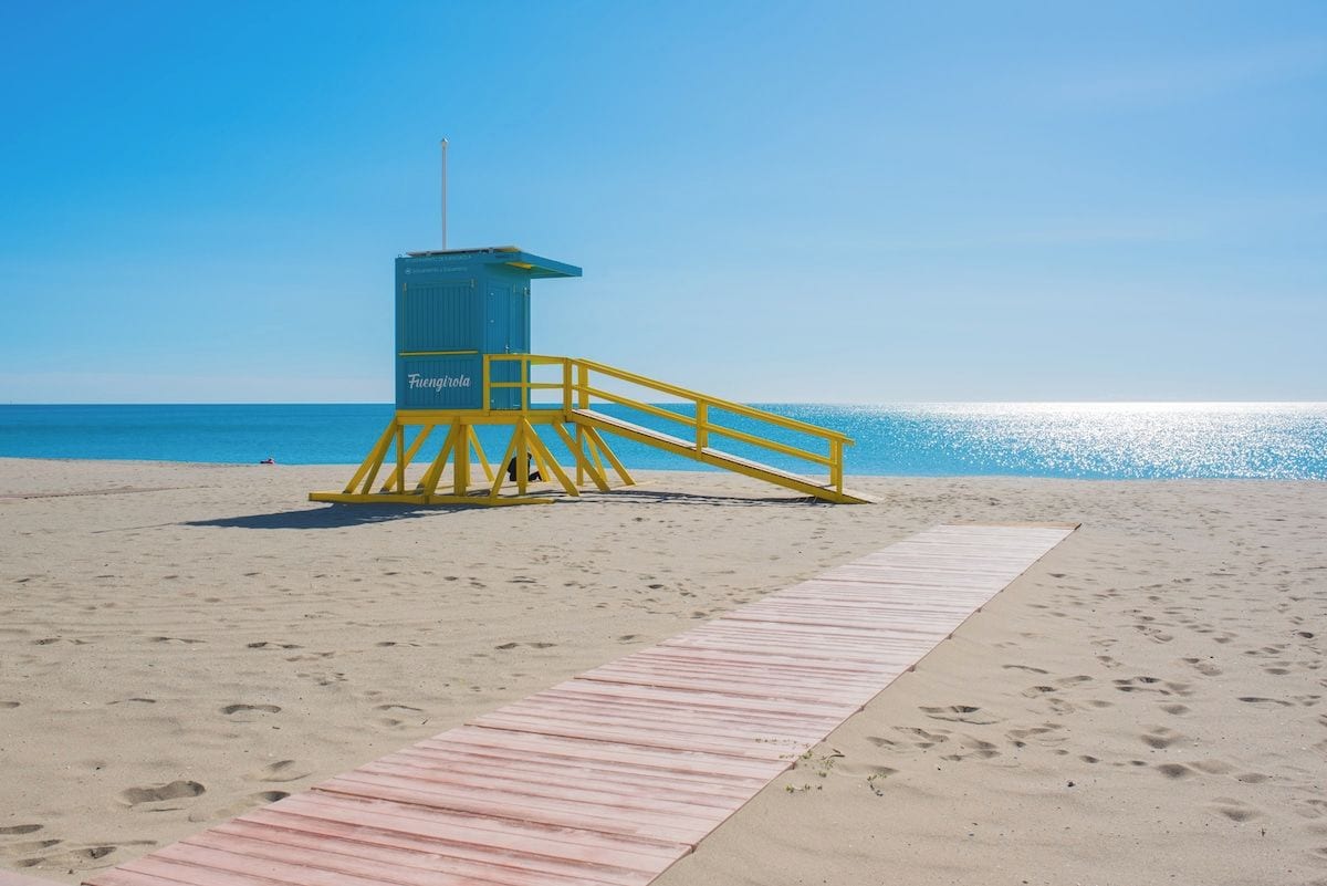 Ein Rettungsturm am sandigen Strand unter blauem Himmel.