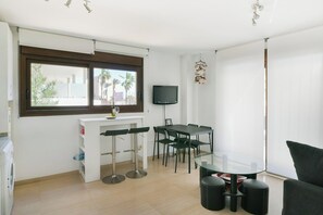 A modern kitchen with a dining area, a TV mounted on the wall, and a window with a view of palm trees. - Lovely apartment 50m from the beach! (Fuengirola)