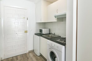 A compact kitchen with a washing machine, a microwave, and a sink.