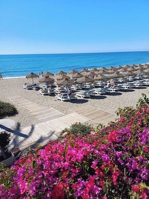 A beach with sun loungers and umbrellas, a wooden deck, and a view of the sea. - Great Apartment Amazing Seaview! 5 Pools, Pool bar (Benalmadena)