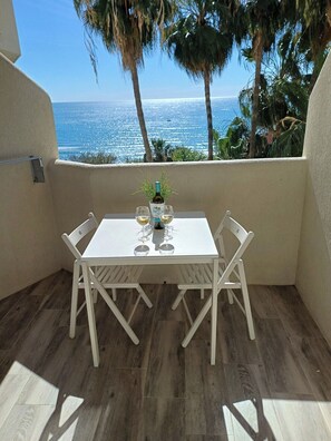 A balcony with a table set for two, overlooking a coastal view. - Great Apartment Amazing Seaview! 5 Pools, Pool bar (Benalmadena)
