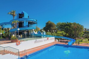 Piscina com escorregador azul e edifício moderno com telhado azul.