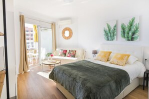 Un dormitorio con una cama, un espejo redondo y dos cuadros con plantas.