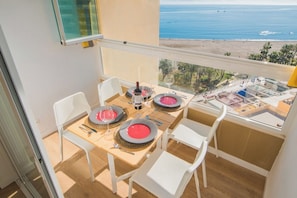 A balcony with a table set for two, overlooking a beach and ocean view. - Nice studio on the beach. (Capellania, La)