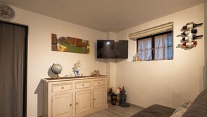 A bedroom with a bed, a TV mounted on the wall, a window with curtains, a cabinet with decorative items, and a globe on the cabinet. - CASA PINA BED & BREAKFAST (Spoltore)