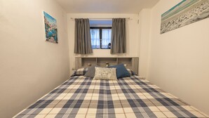 A bedroom with a checkered bedspread, a window with curtains, and two wall-mounted paintings. - CASA PINA BED & BREAKFAST (Spoltore)