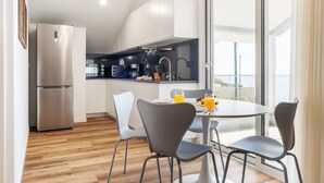 Eine moderne Küche mit einem Edelstahlkühlschrank, weißen Schränken und einem Essbereich mit rundem Tisch und zwei Stühlen.