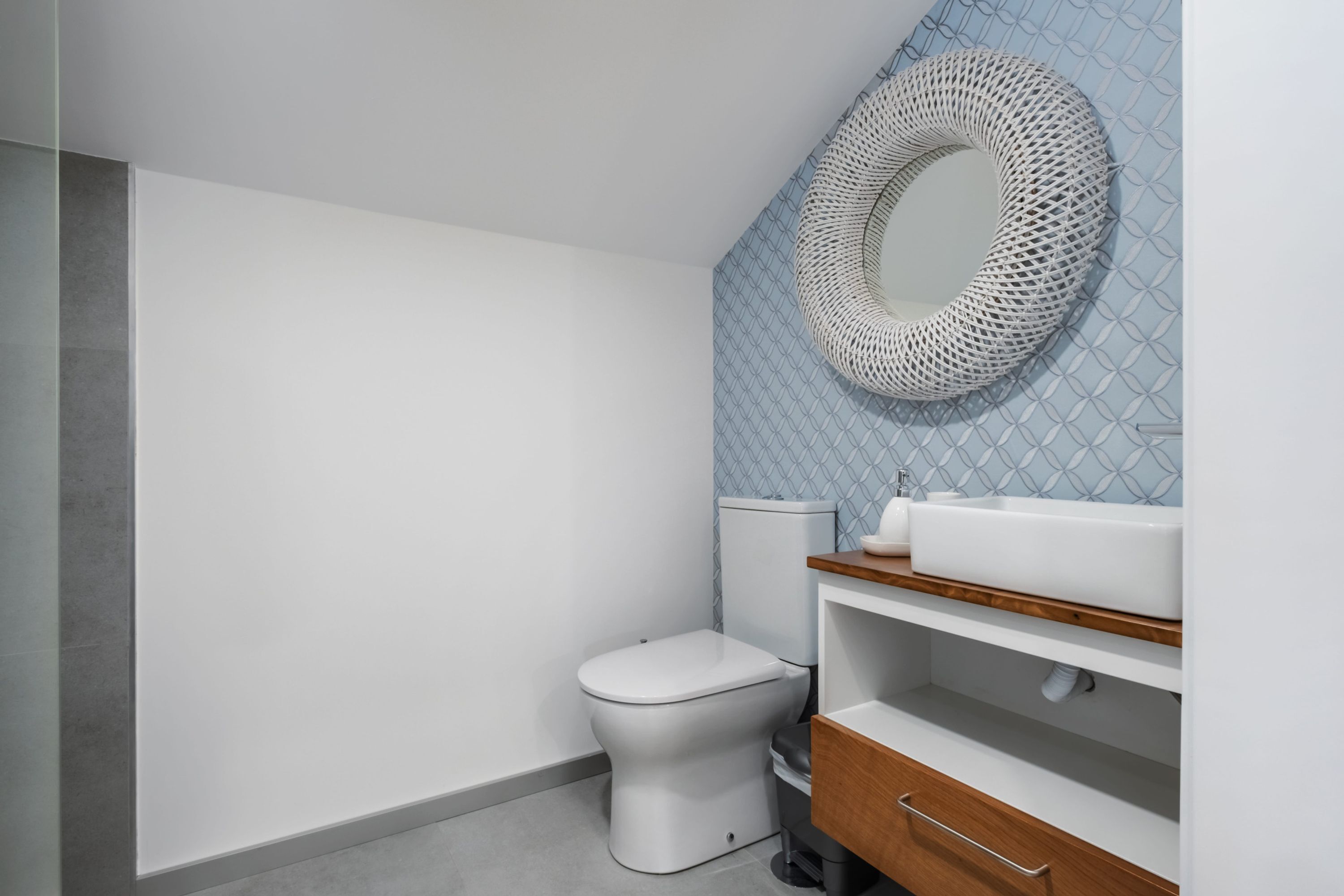 Un baño moderno con inodoro, lavamanos y un espejo decorativo.