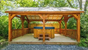 A wooden gazebo with a bench and a table, surrounded by a wooden fence and trees. - Seneca Hideaway/Sunken Vessel/Hot Tub (Geneva)