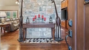 A living room with a stone fireplace, a wooden coffee table with red candles, and two giraffe statues.