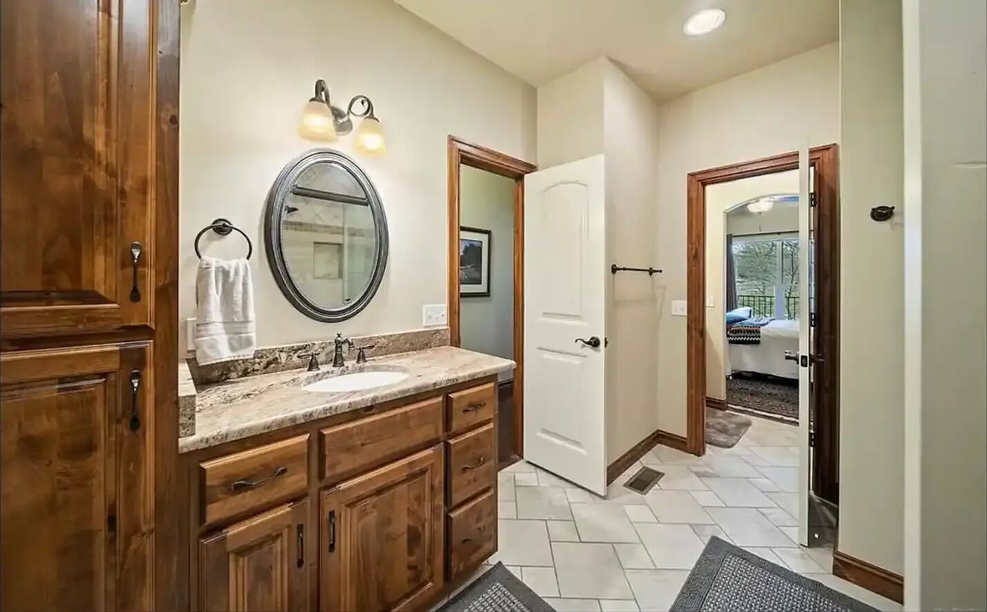 A bathroom with wooden cabinets, a double sink vanity, a large mirror, and a shower area.