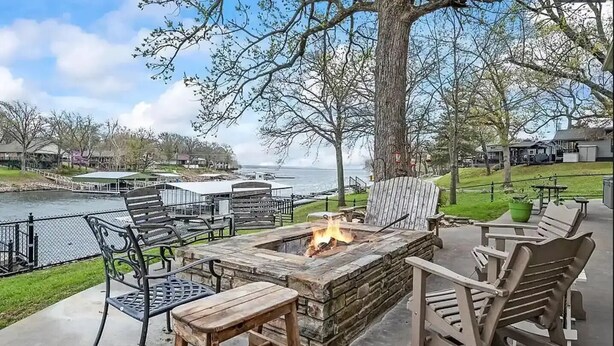 An outdoor seating area with a fire pit, chairs, and a view of a body of water.