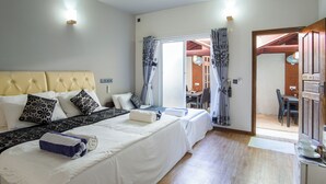 A hotel room with a large bed, a desk, and a dining area visible through an open door. - Palm Oasis at Ukulhas (Ukulhas)