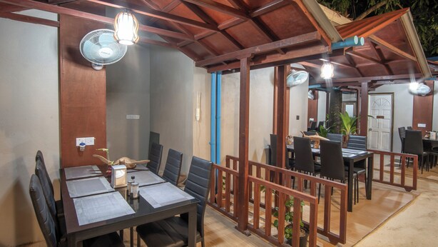 A restaurant with wooden tables and chairs, fans, and a view of the outdoors. - Palm Oasis at Ukulhas (Ukulhas)